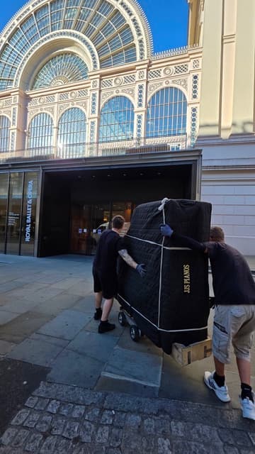 JJS Pianos specialist moving a wrapped piano